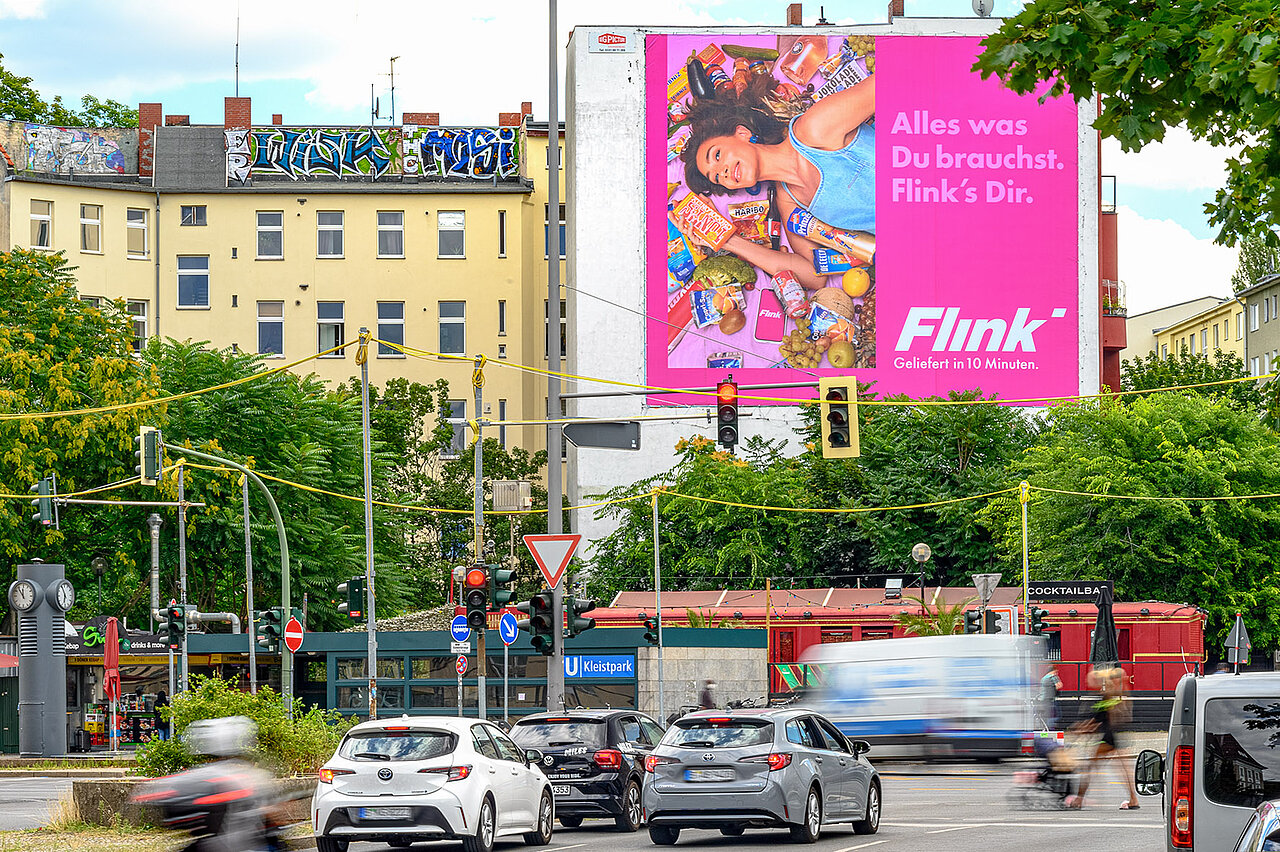 Riesenposter von Flink auf einem Gebäude in der Stadt, mit einer Werbung für schnelle Lieferung in 10 Minuten. Leuchtendes, großes Plakat an einem gut sichtbaren Standort.