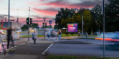 Werbeplakat mit dem Slogan 'Übersehen unmöglich' an einer belebten Straßenecke. Es ist gut sichtbar für Fußgänger und Autofahrer, die die Kreuzung passieren."