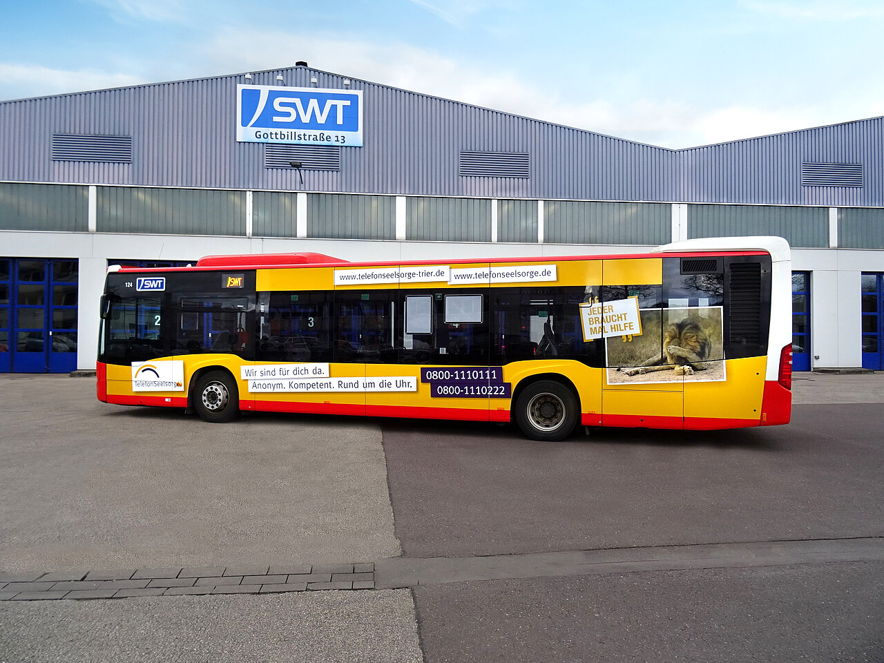 Teilgestaltung eines Busses für die Telefonseelsorge Trier. Auf der Seite des Busses ist der Slogan „Jeder braucht mal Hilfe“ zu sehen, begleitet von der Telefonnummer und einer Notfallnummer für Unterstützung.
