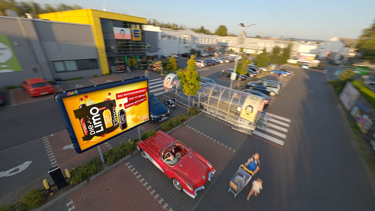 Großes 9-qm-Werbeplakat mit „Die Limo“-Motiv auf einem belebten Supermarkt-Parkplatz, umgeben von Autos, Einkaufswagen und vorbeigehenden Menschen – buchbar über Plakat-verkauft.de.