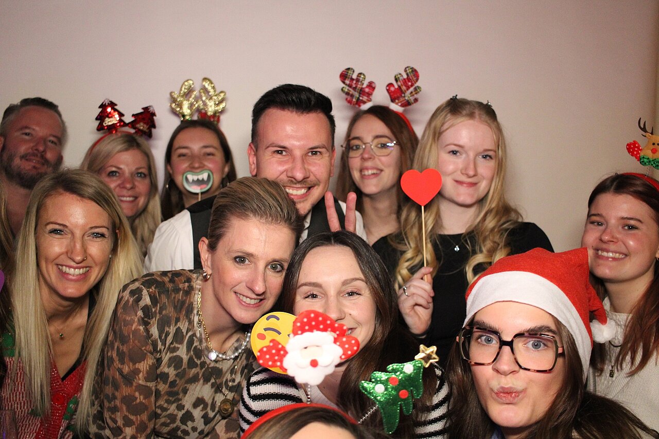 Team von Plakat-verkauft.de bei der fröhlichen Weihnachtsfeier, gemeinsam lachend und mit festlichen Accessoires