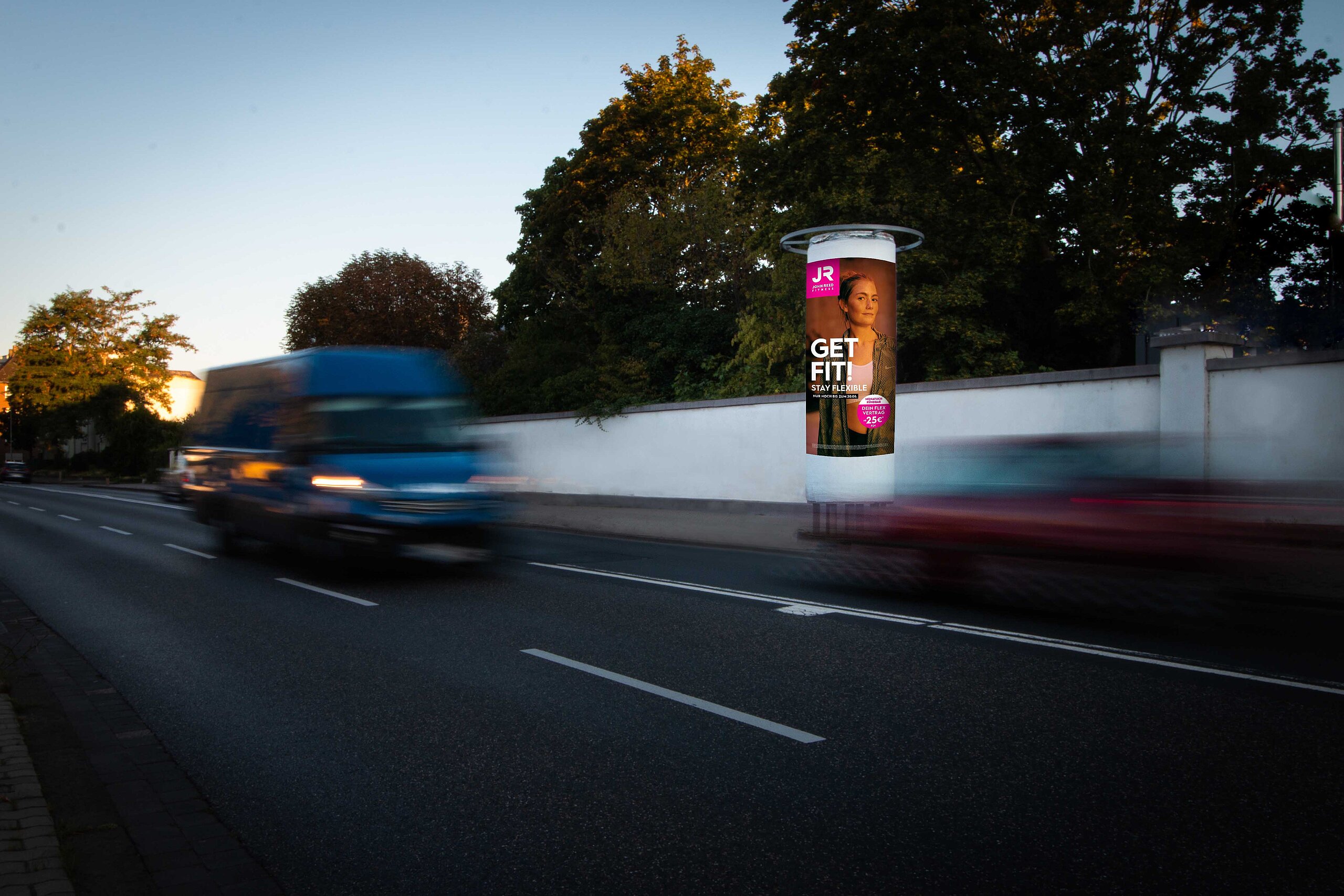 Ganzsäule mit Werbung für JR Fitness, mit einem beeindruckenden visuellen Auftritt in der Abenddämmerung. Werbepräsenz auf 3 Plakaten für eine umfassende Markenwirkung.