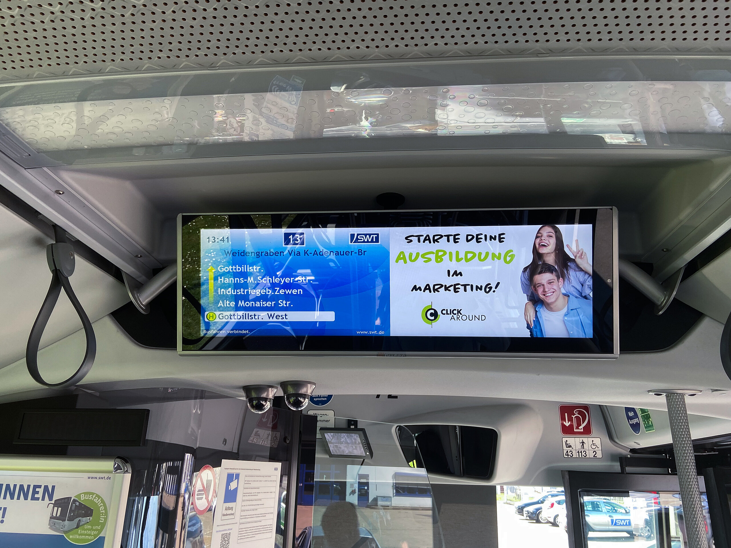 Digitaler Bildschirm im Bus, der Werbung für die Ausbildung im Marketing bei ClickAround anzeigt und den Fahrgästen während der Fahrt Informationen bietet.