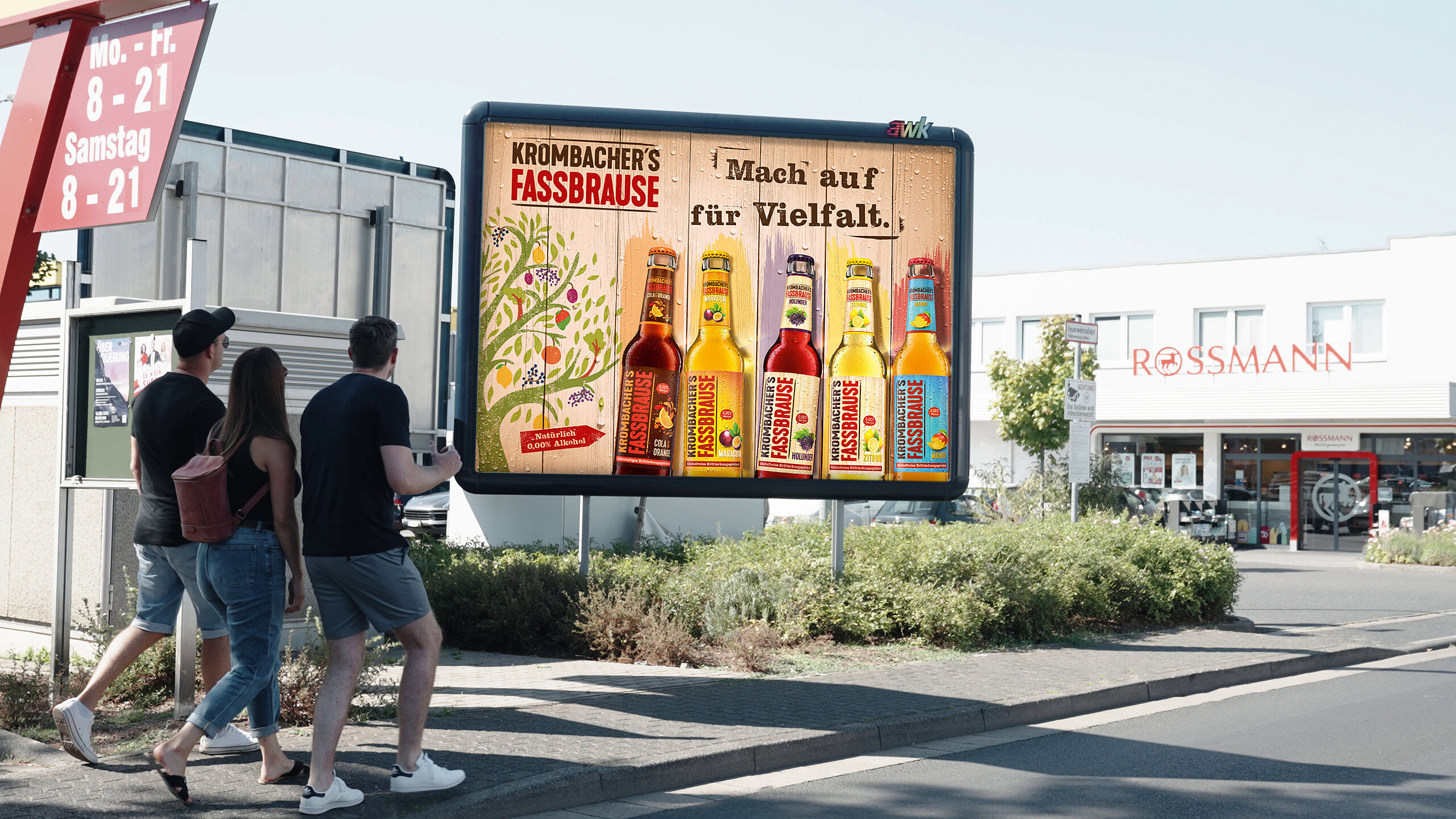 Großplakat vor einem Einkaufsmarkt mit buntem Fassbrause-Motiv, drei Personen bleiben stehen und betrachten die Werbung – buchbar über Plakat-verkauft.de.