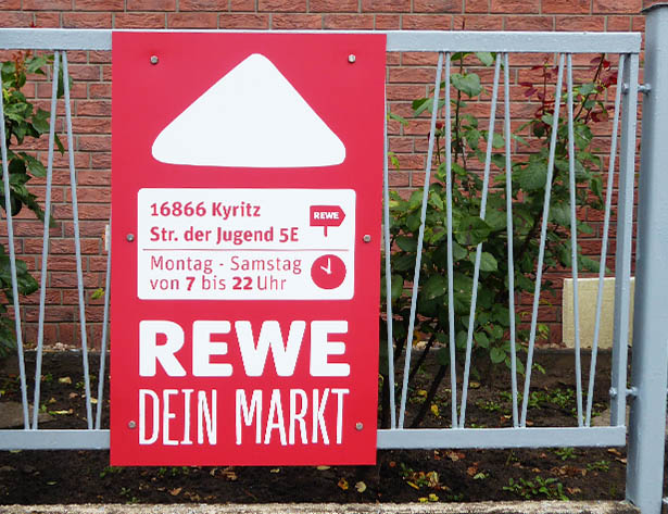 City Board mit der Aufschrift „REWE Dein Markt“ für Außenwerbung mit einer Mindestlaufzeit von 36 Monaten. Ideal für langfristige und gezielte Markenansprache.